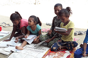 Jungen und Mädchen in Rautahat schreiben auf Papier auf dem Boden sitzend