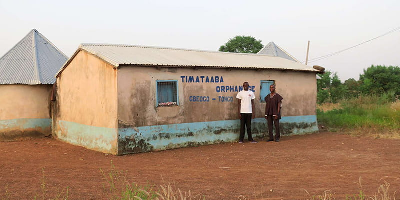 Entwicklungshelfer aus Ghana vor Haus in Timataaba